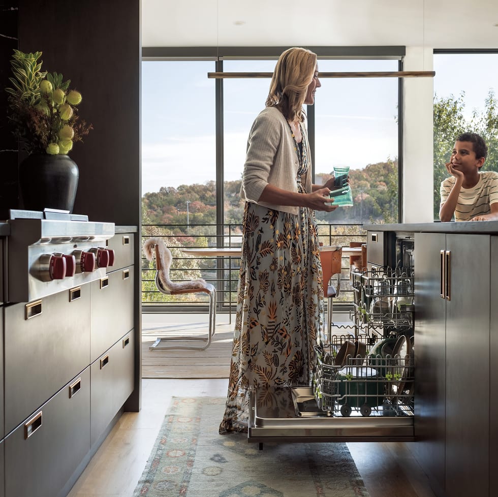 Woman and her child in their kitchen with dishwasher open.