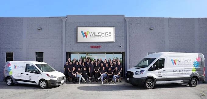 Wilshire Refrigeration & Appliance Inc. team standing in front of company headquarters with branded service vans