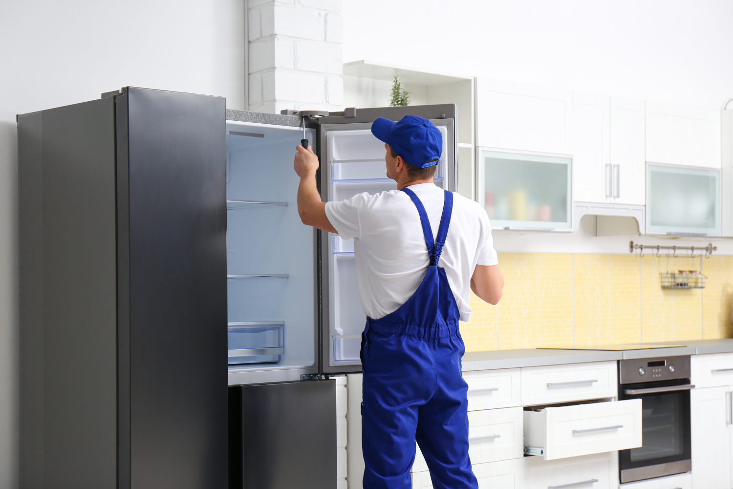 Factory certified technician in blue uniform inspecting the interior components of a luxury refrigerator to see how long do refrigerators last