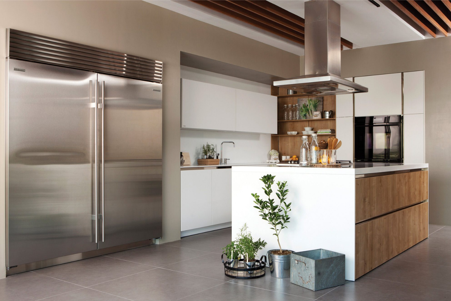 Modern kitchen with double-door fridge, white cabinets, central island, and potted plants on the floor