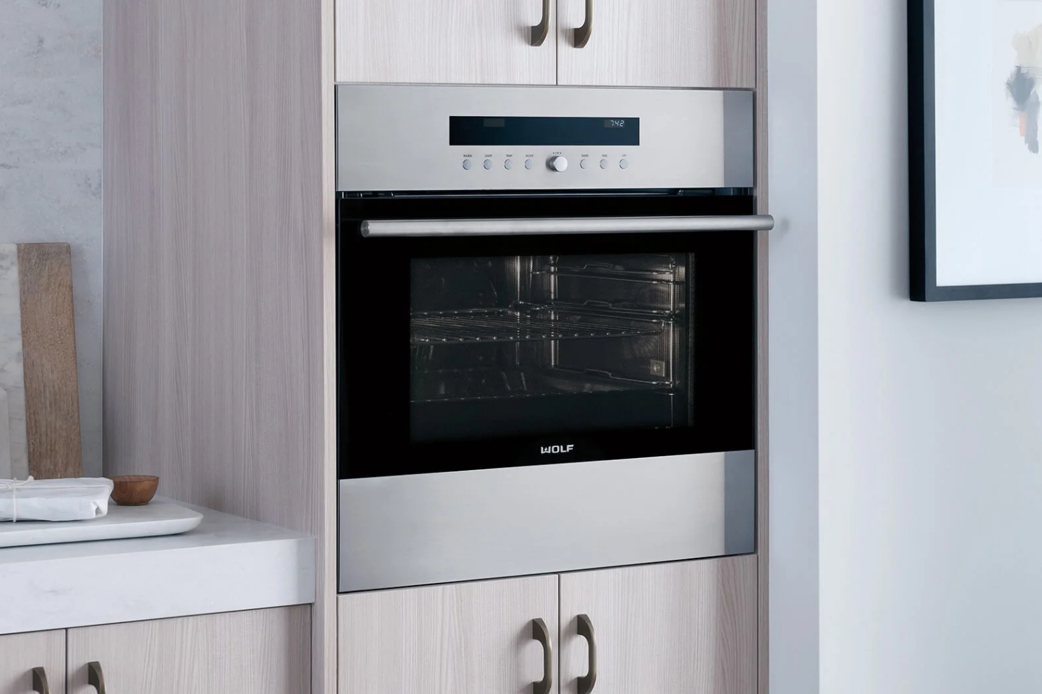 Built-in stainless steel WOLF oven with digital controls in a modern kitchen cabinet.