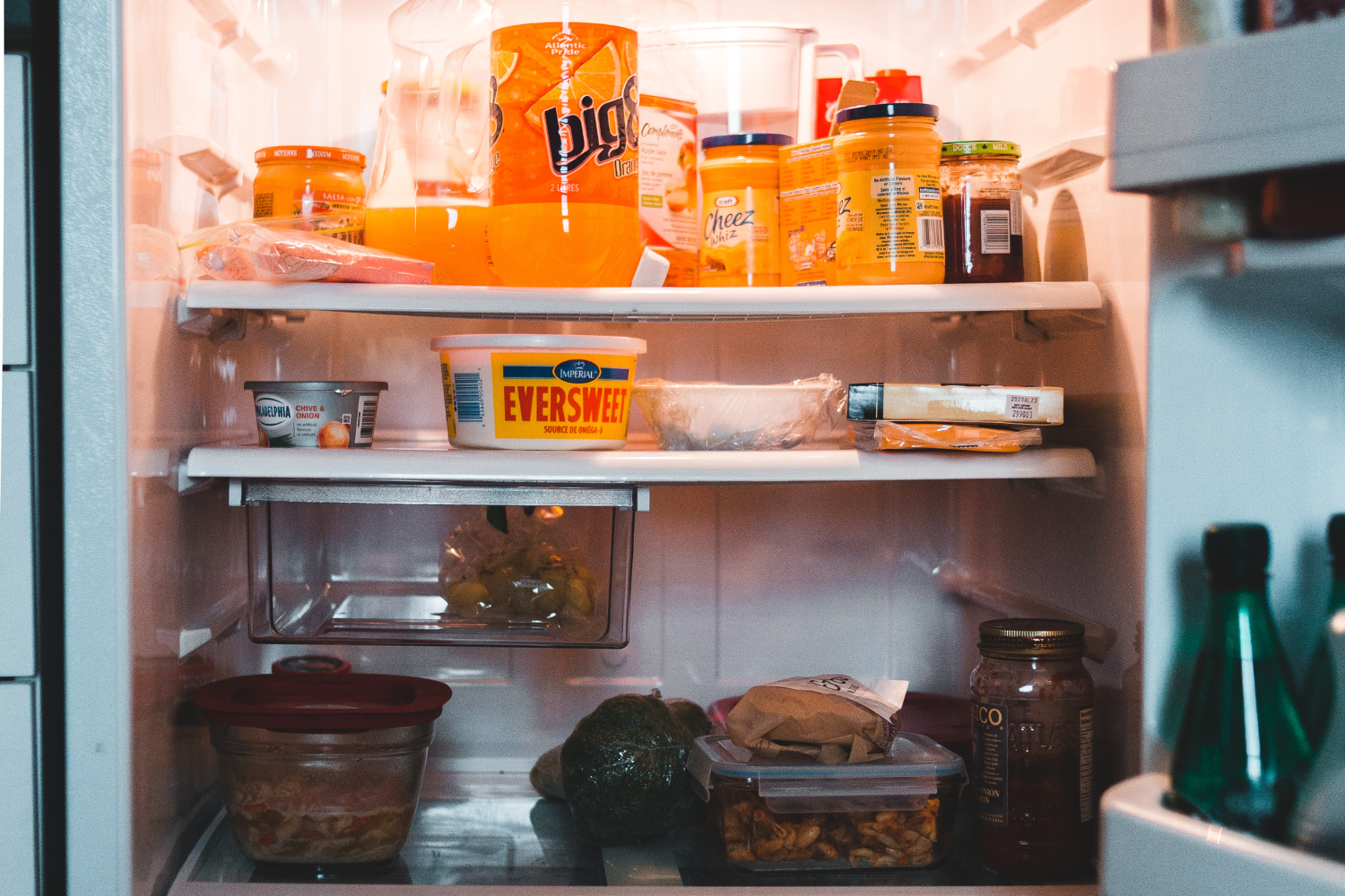 A refrigerator stocked with various food items including jars, containers, and bottles on shelves and in drawers.