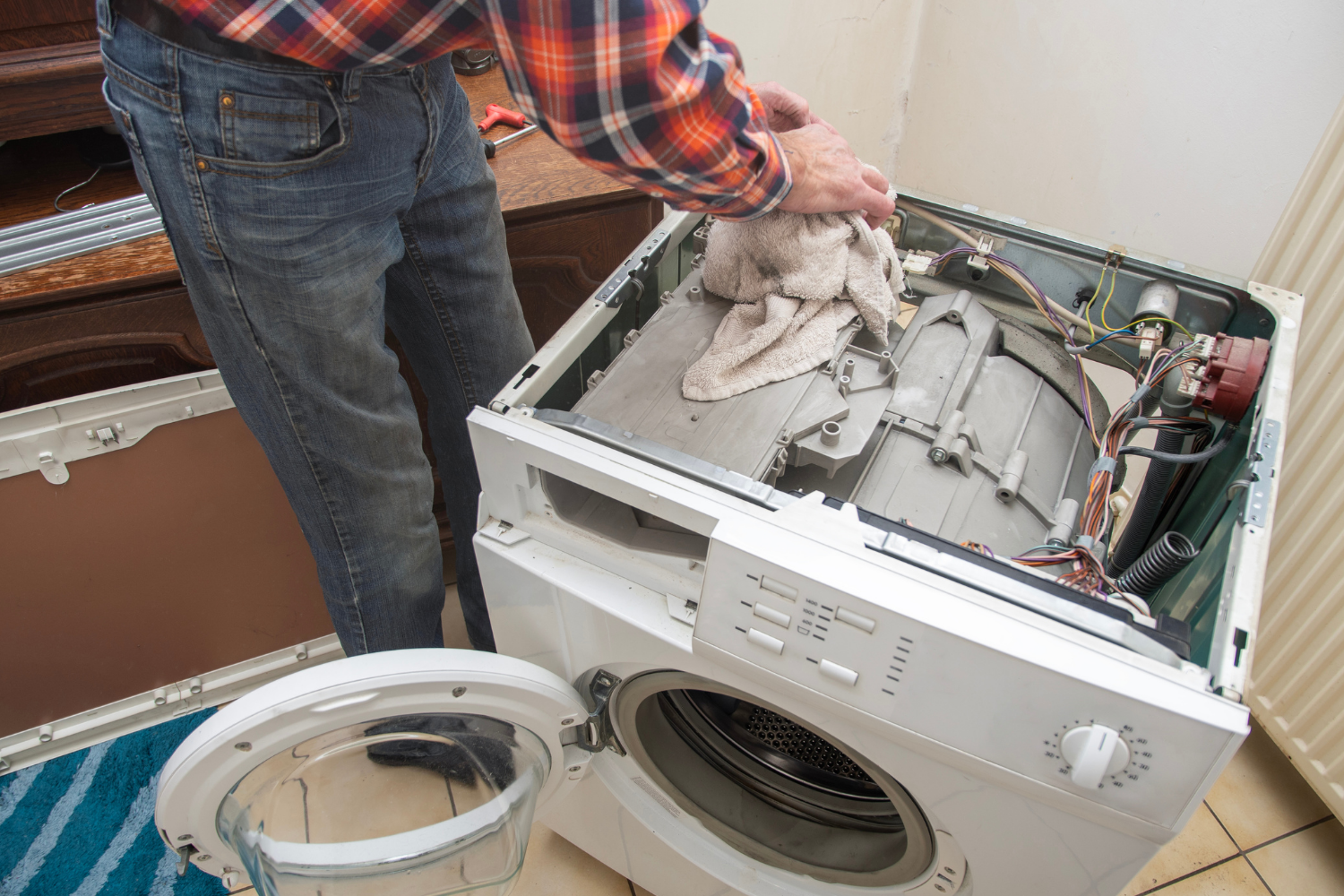 A person is cleaning the inside of a washing machine with a cloth.
