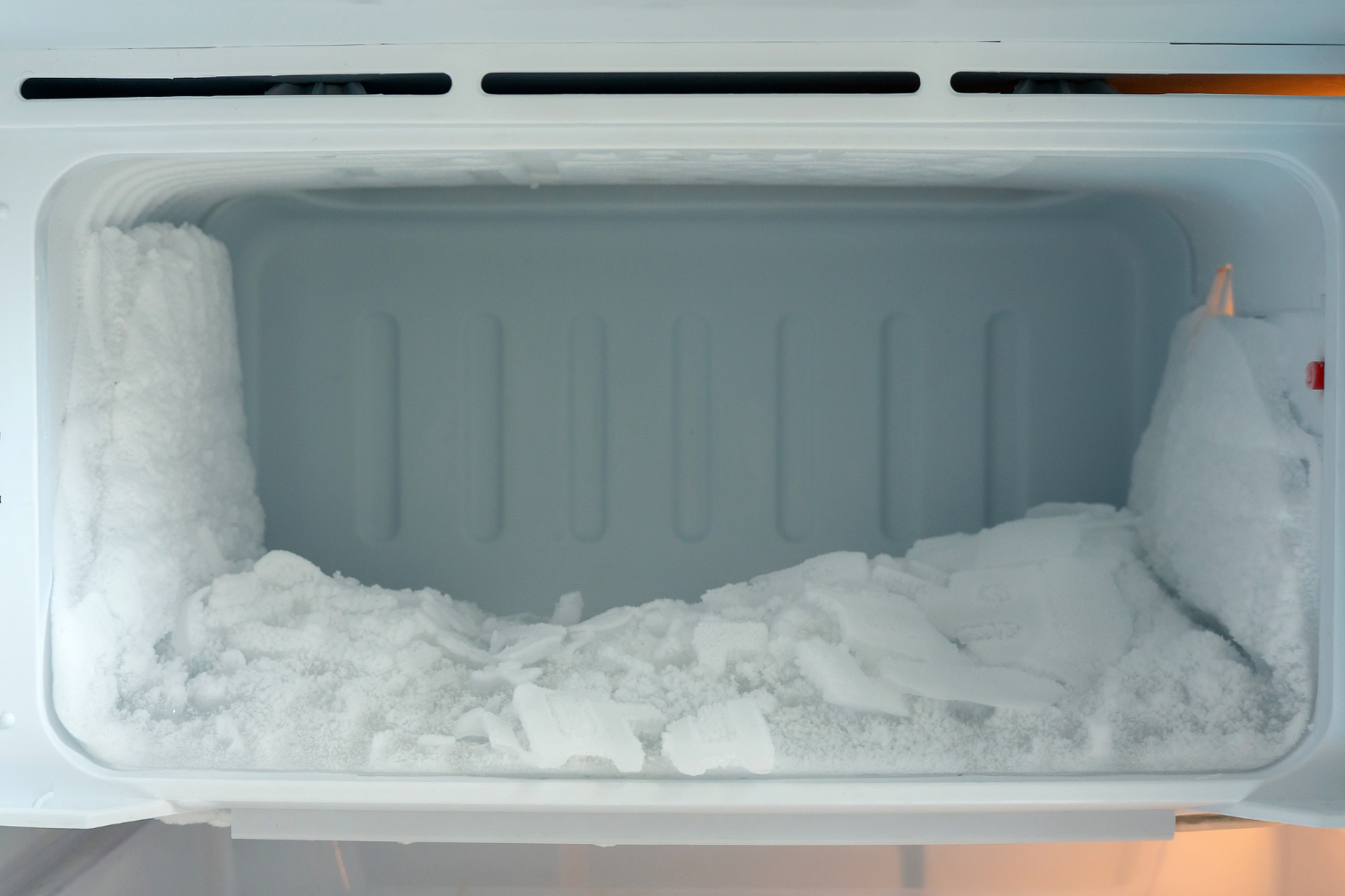 Interior of freezer with heavy frost and ice buildup on shelves, showing how poor sealing or frequent door opening can cause frost accumulation.