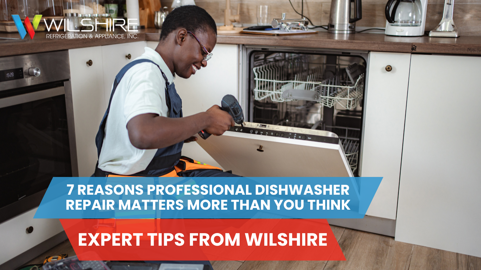 A person wearing a blue uniform and an orange tool belt kneels in front of an open dishwasher, holding a drill.