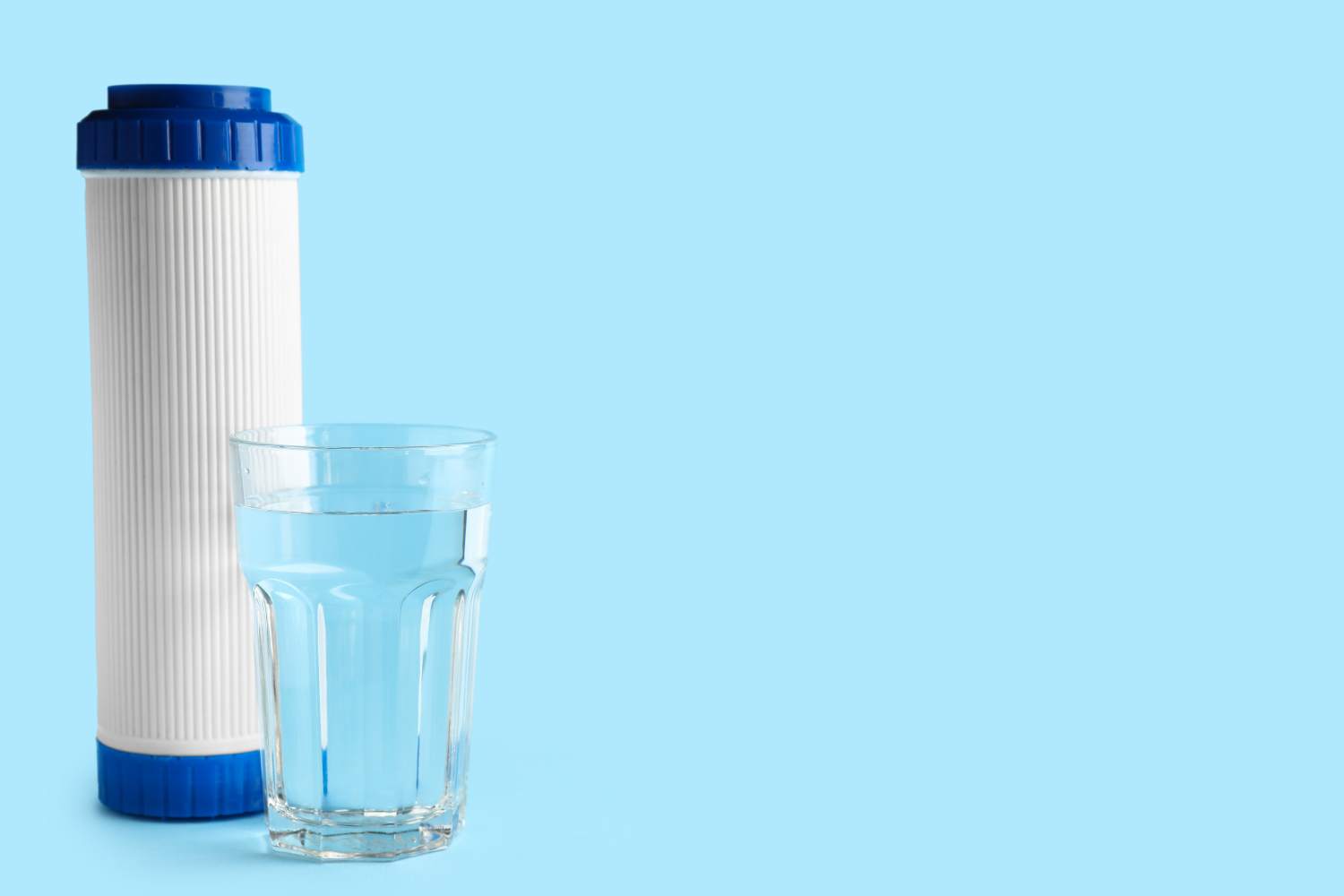 Refrigerator water filter replacement cartridge beside a glass of clean drinking water