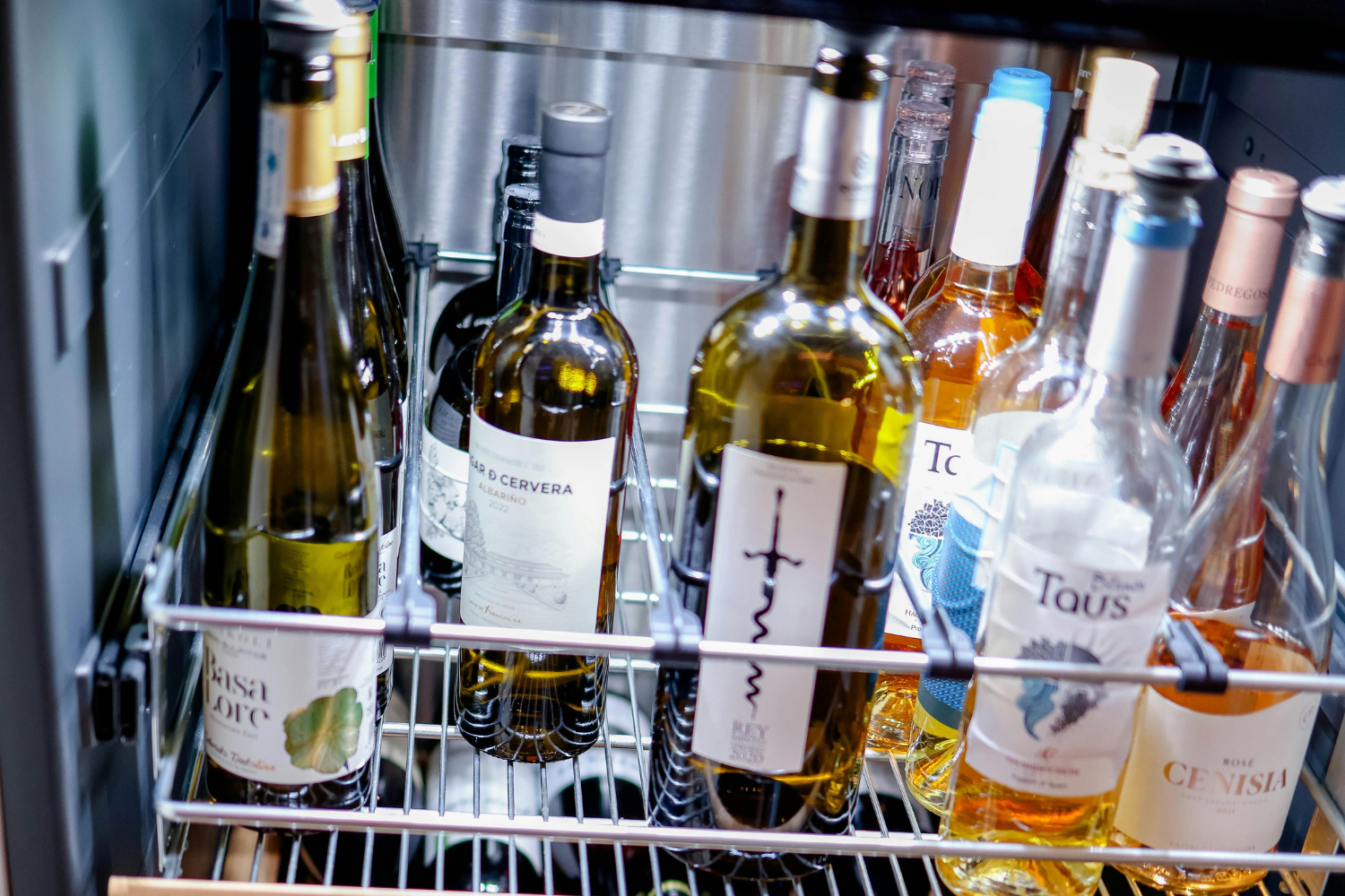 Wine cooler not cooling with assorted bottles stored in metal racks inside refrigerator