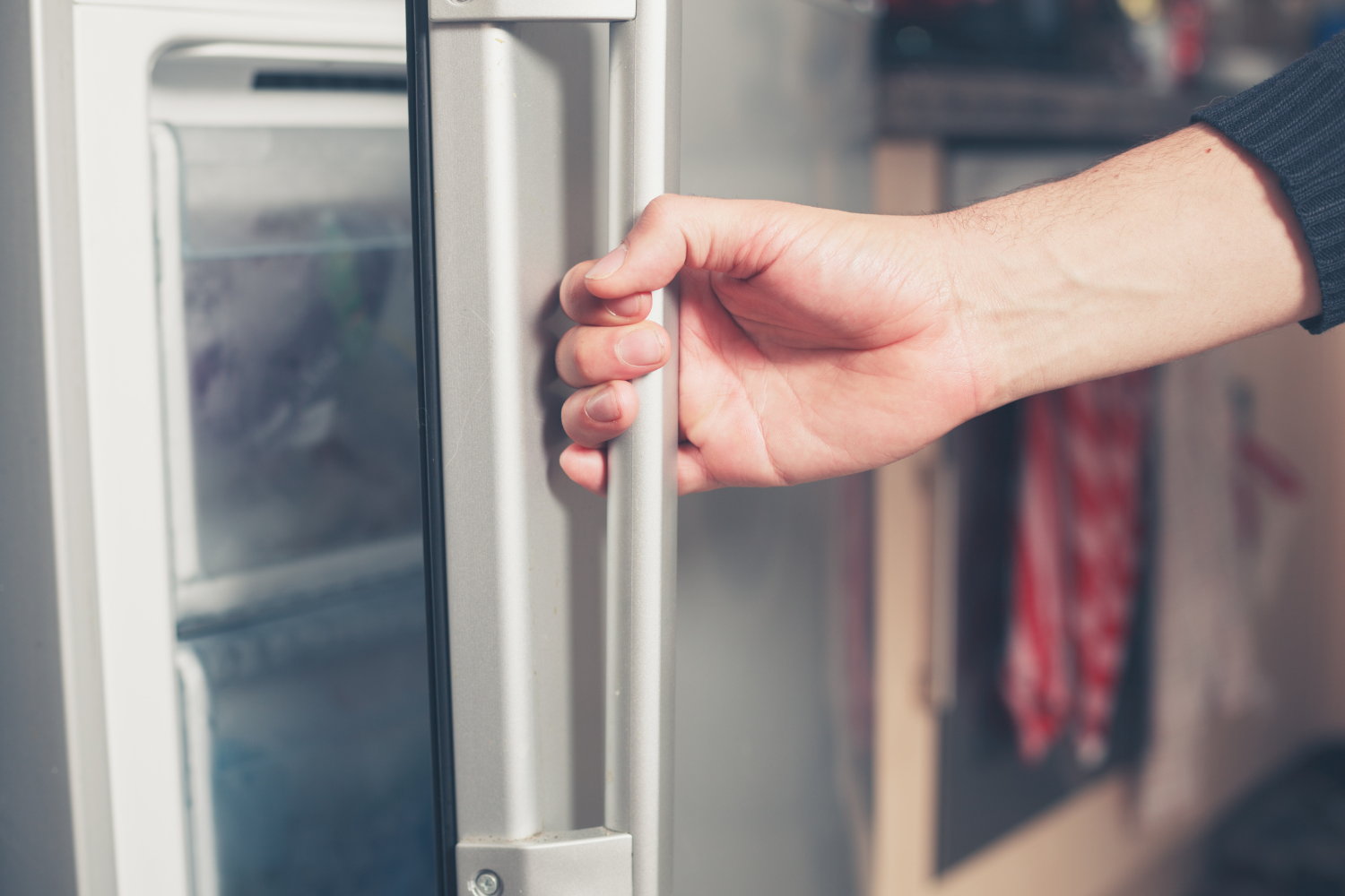 Hand closing a freezer door after it was left open overnight to help restore cooling and prevent food spoilage