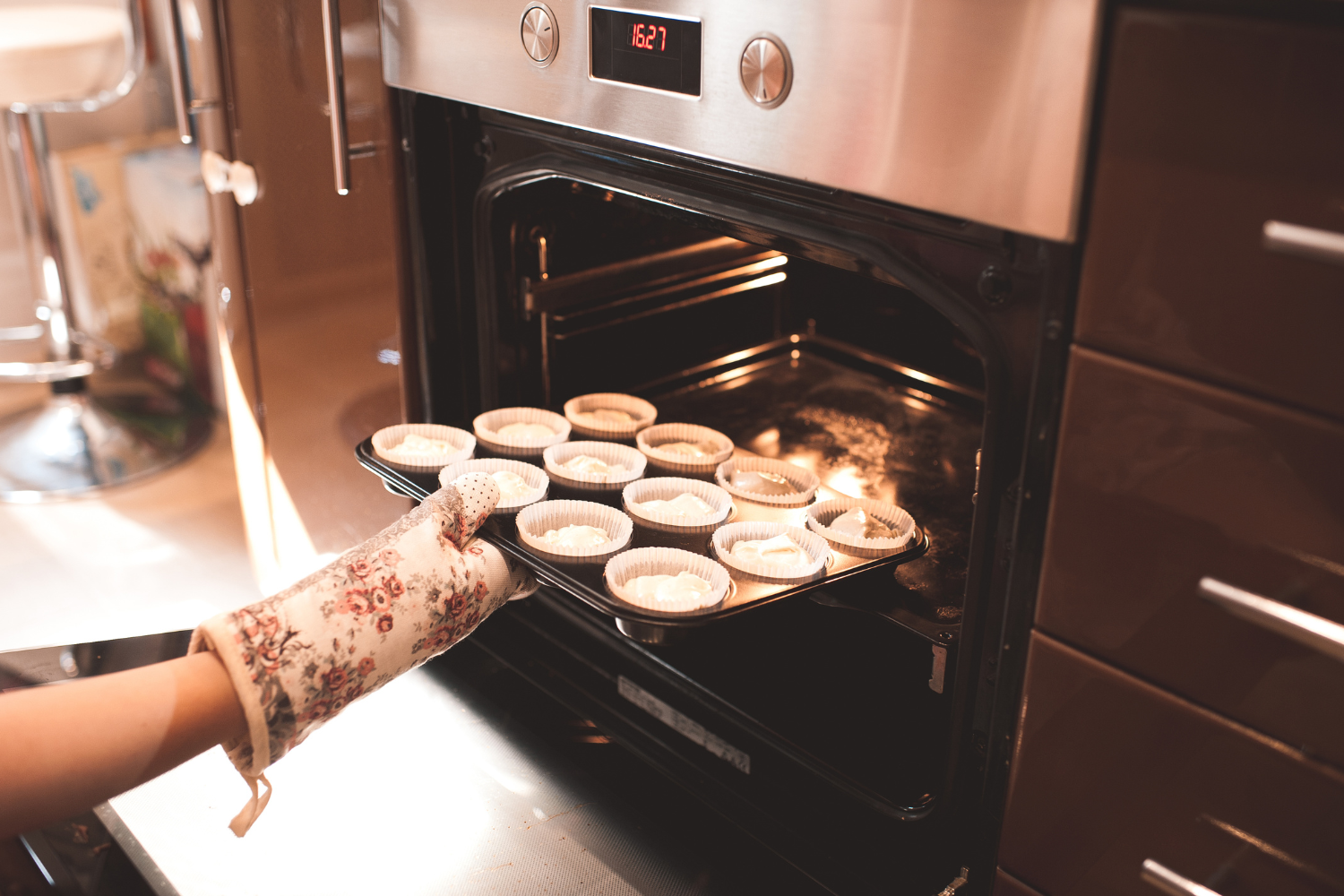 Person placing a baking tray into an oven while troubleshooting why a Miele oven is not heating up.