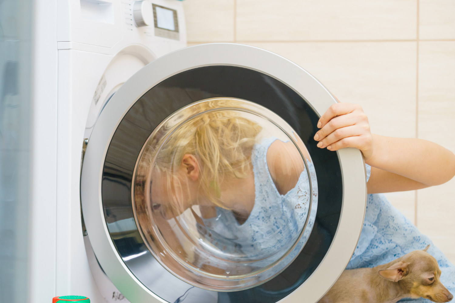 Person inspecting a front-load washer door while troubleshooting Miele washer F20 or F50 error codes.