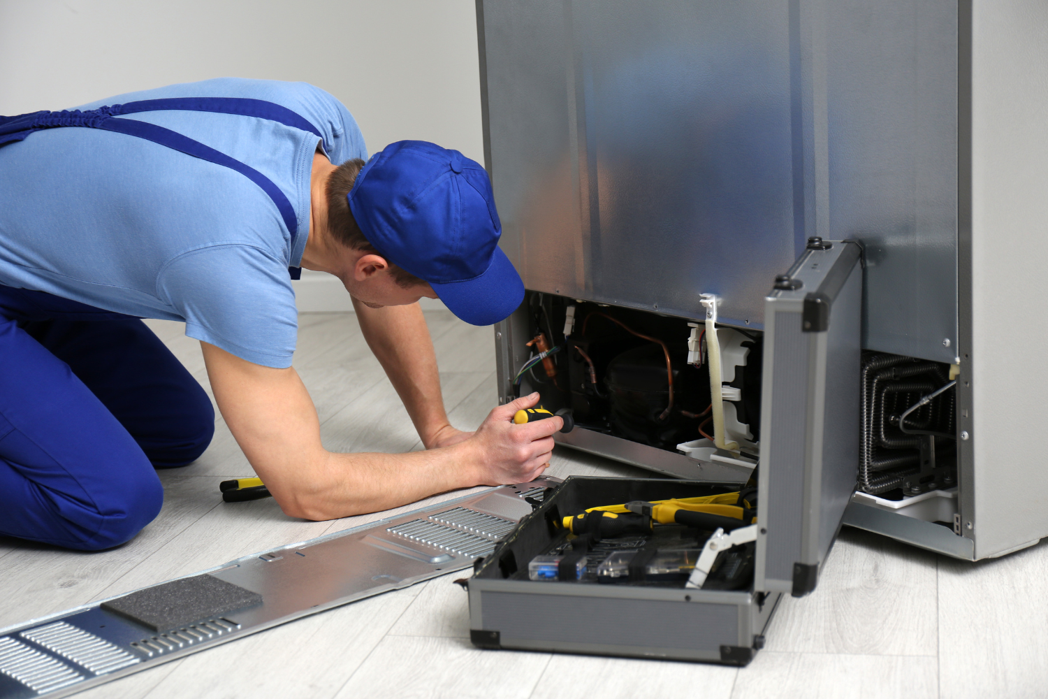 Technician inspecting refrigerator parts during Sub-Zero OEM parts repair and replacement service.