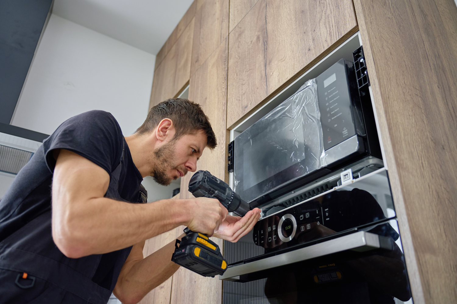 Technician performing Viking oven repair on a built-in kitchen appliance with control and heating components exposed