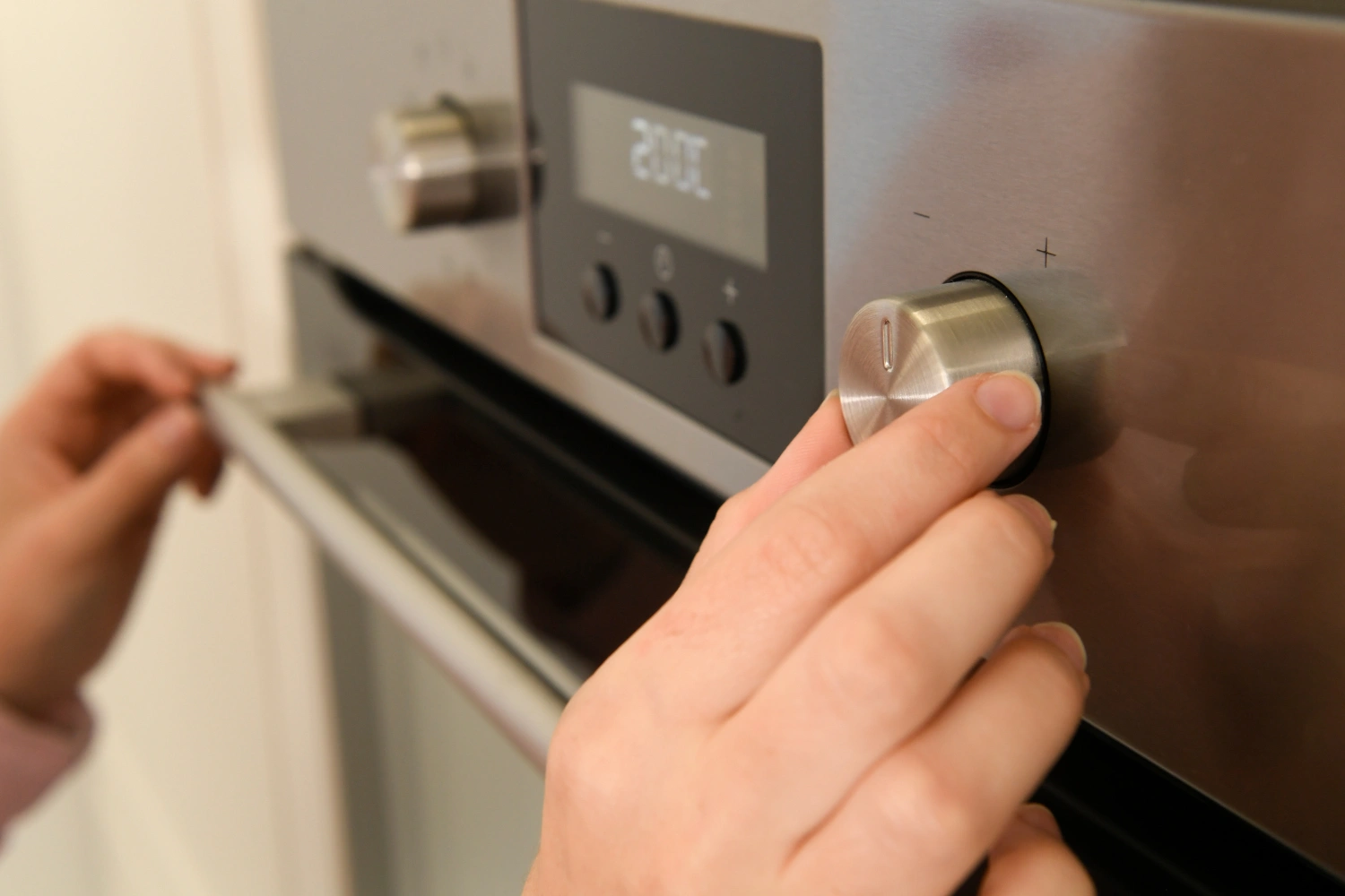Hand adjusting an oven control knob for Viking oven repair warning signs