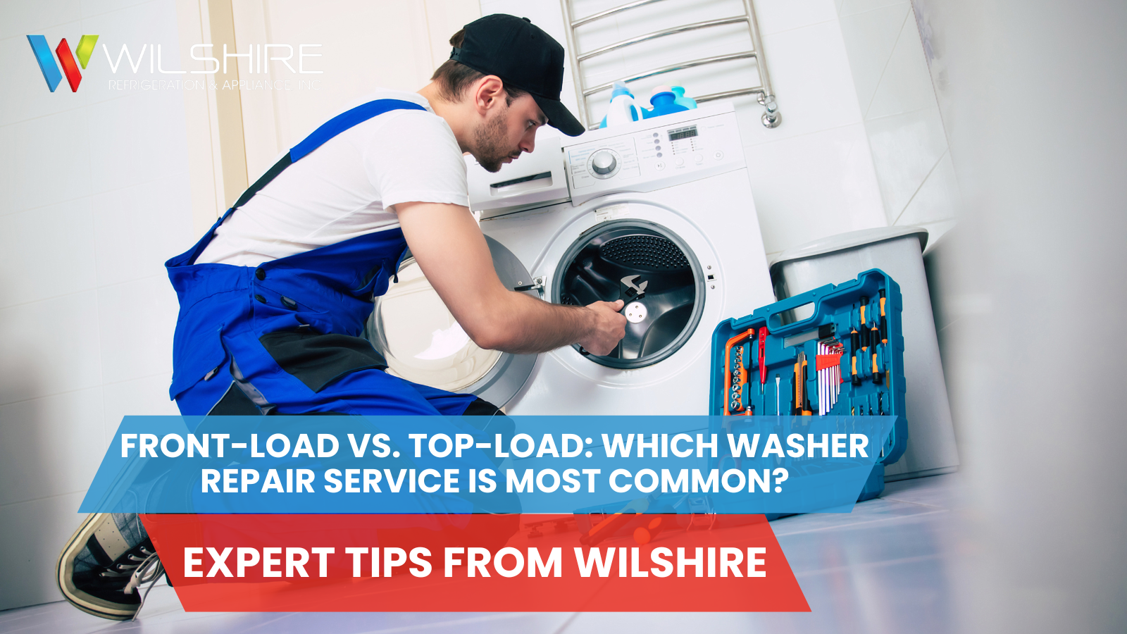 A person in blue overalls kneels to repair a washing machine, with a toolbox and tools nearby.