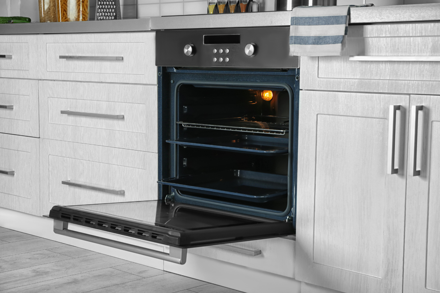 Open built-in wall oven installed in a modern kitchen with the oven door lowered.