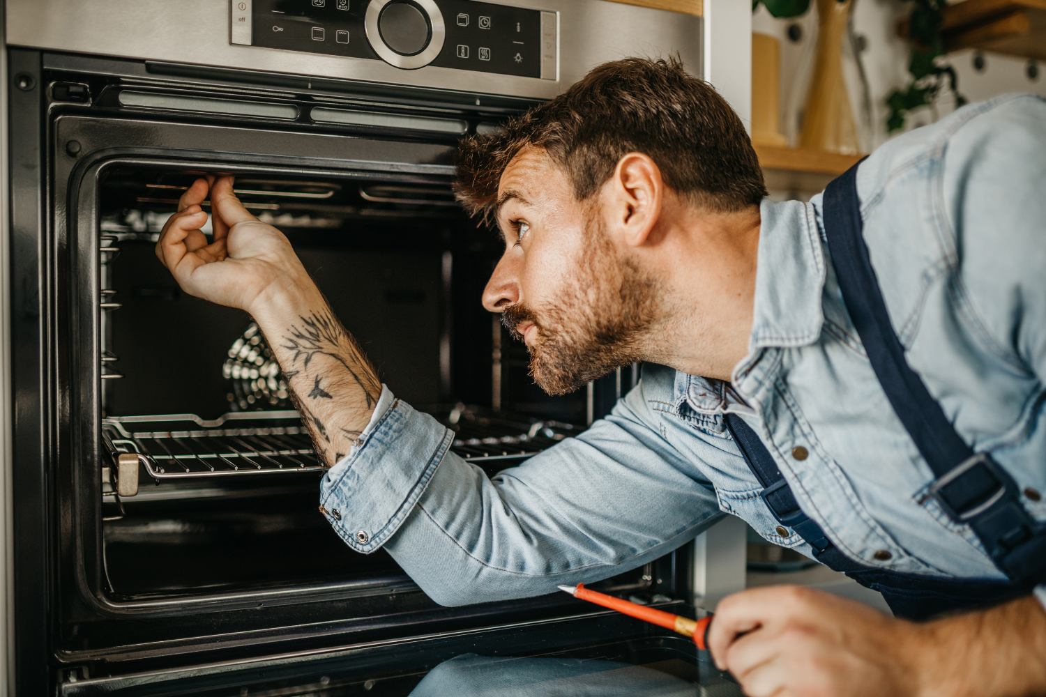 Technician checking a built-in oven interior for Gaggenau oven repair, heating issues, and appliance service.
