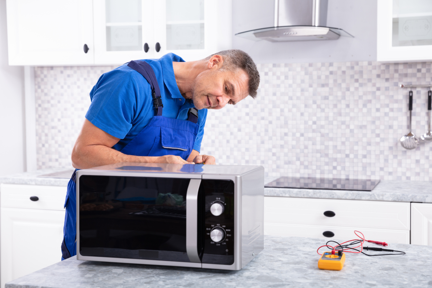 Professional appliance repair technician examining a microwave with diagnostic equipment in a modern kitchen.