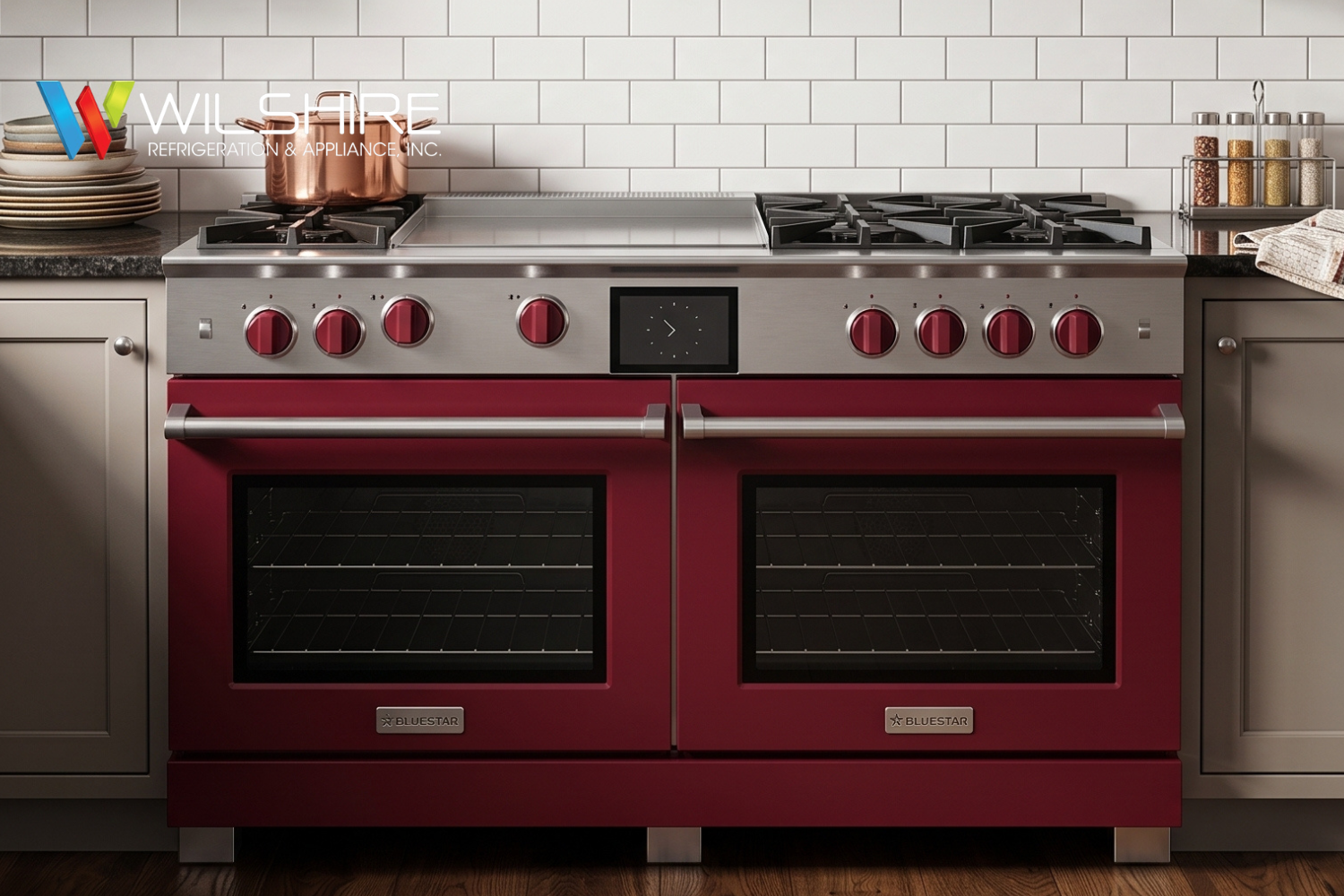 Modern kitchen with gray cabinetry, a red Bluestar double oven range with black burners, white subway-tile backsplash, copper cookware on the counter, and a stainless hood above the stove.