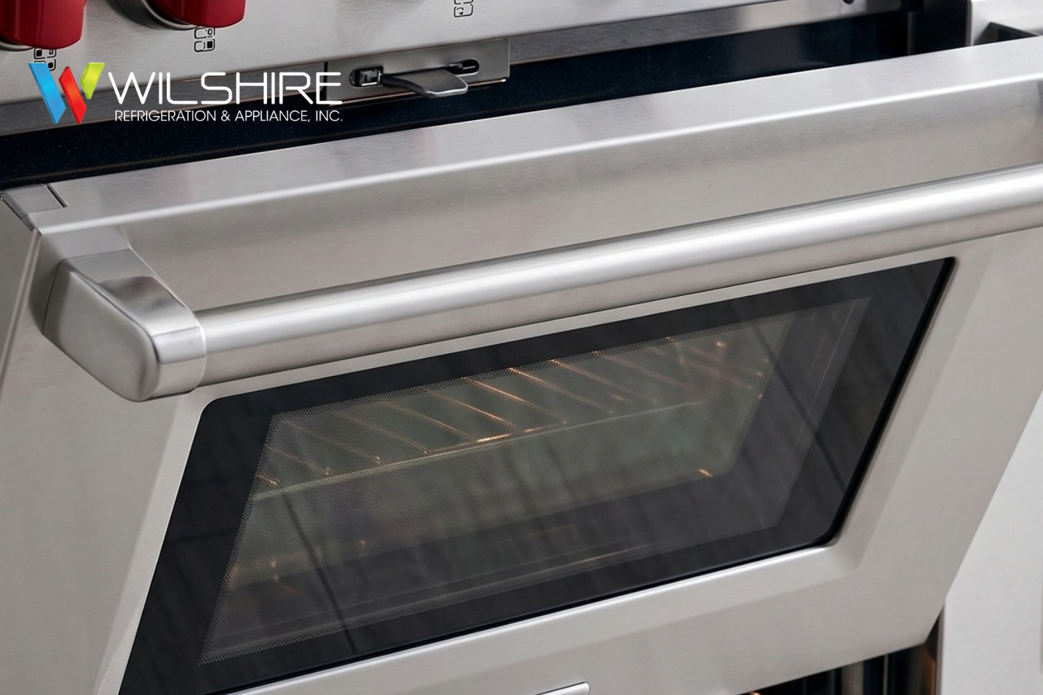 Wolf stainless steel double oven and six‑burner gas range with signature red knobs, featuring one oven door partially open to show interior racks.