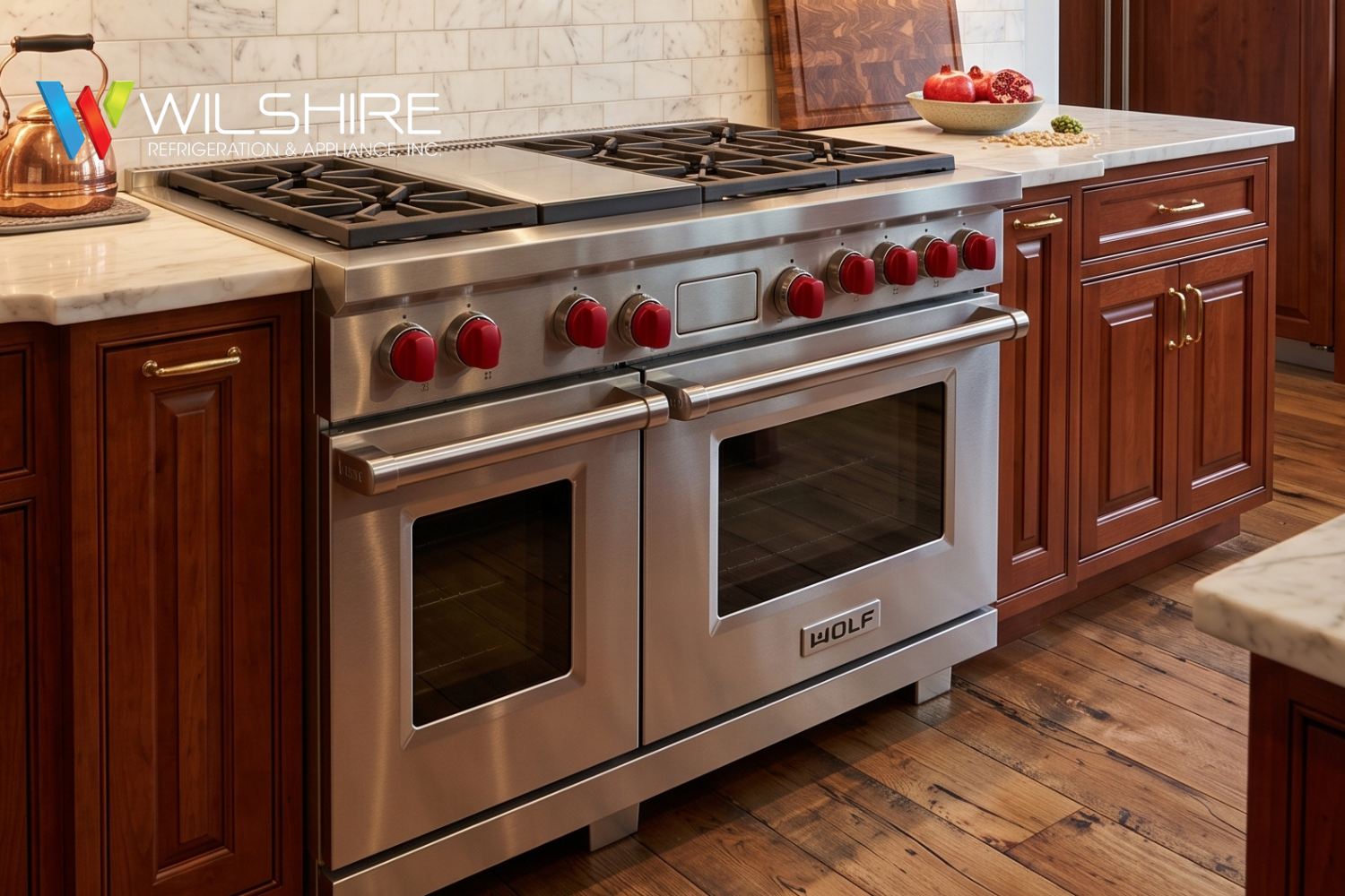 Modern kitchen with stainless steel Wolf double oven and six‑burner gas range featuring signature red knobs, set against marble countertops and subway tile backsplash.