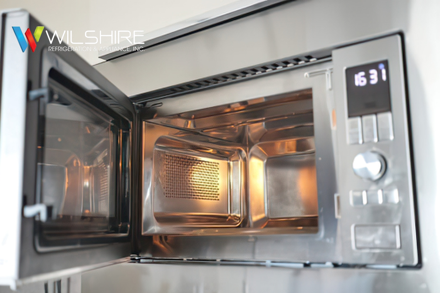 Open Wolf built-in microwave with stainless steel interior, illuminated cavity, and digital control panel visible on the side.