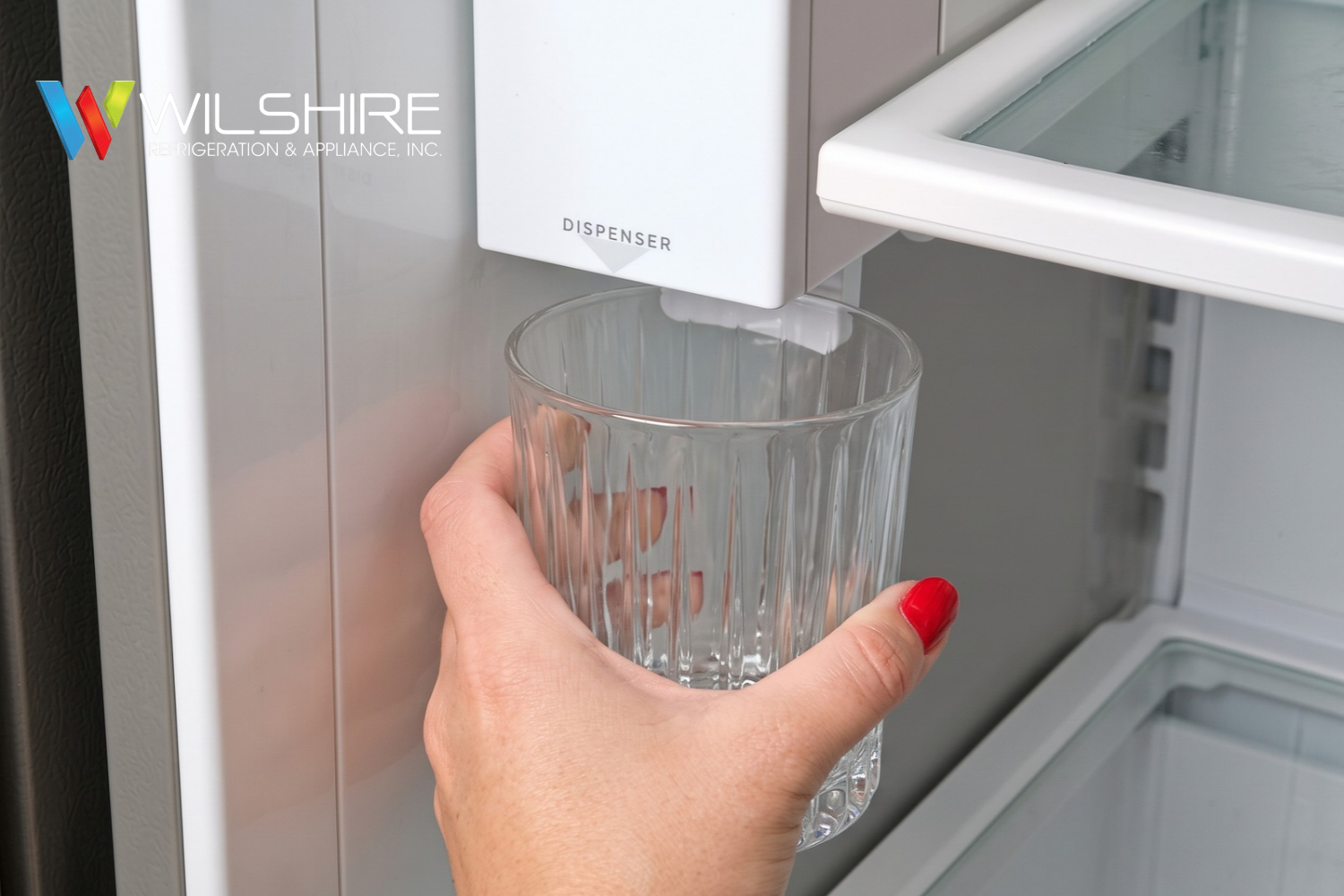 Close‑up of Sub‑Zero refrigerator water dispenser with glass held underneath