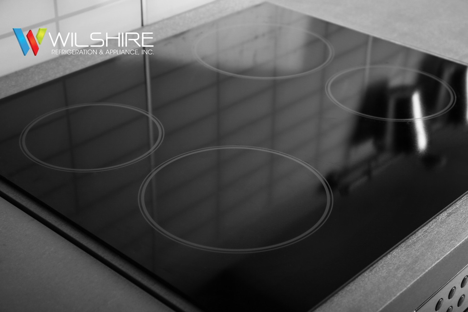 Wolf induction cooktop with four cooking zones and smooth black glass surface installed in a modern kitchen countertop.