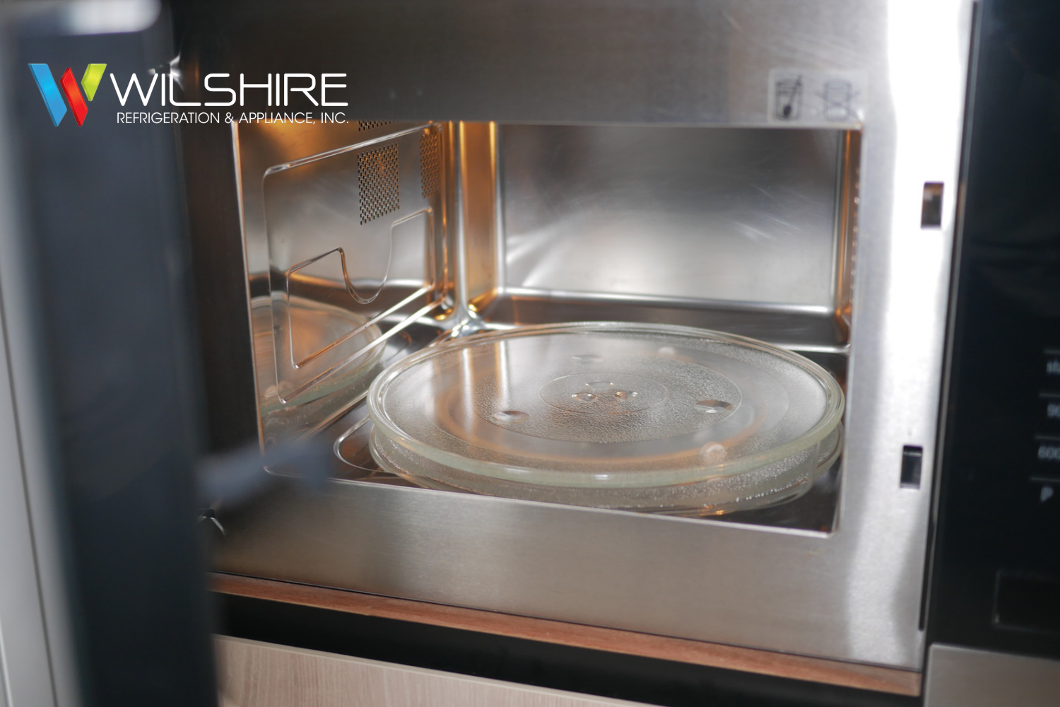 Wolf microwave interior with removable glass turntable plate inside stainless steel cooking cavity.