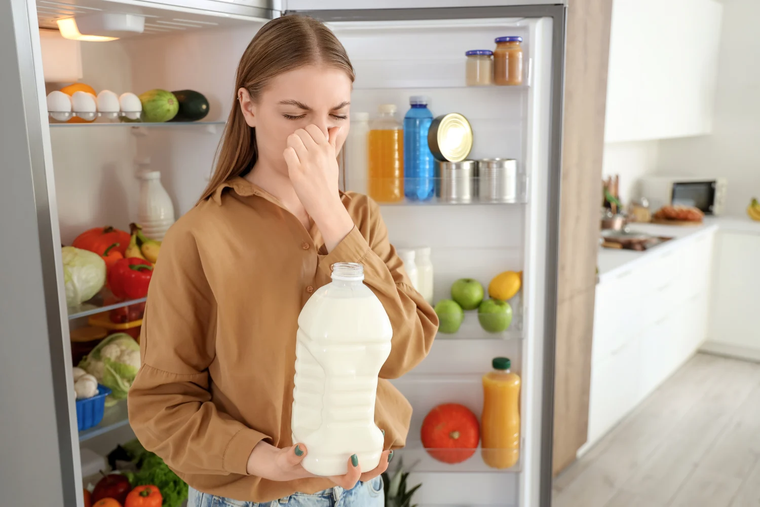 Woman holding spoiled milk in front of an open refrigerator needing Viking refrigerator repair service